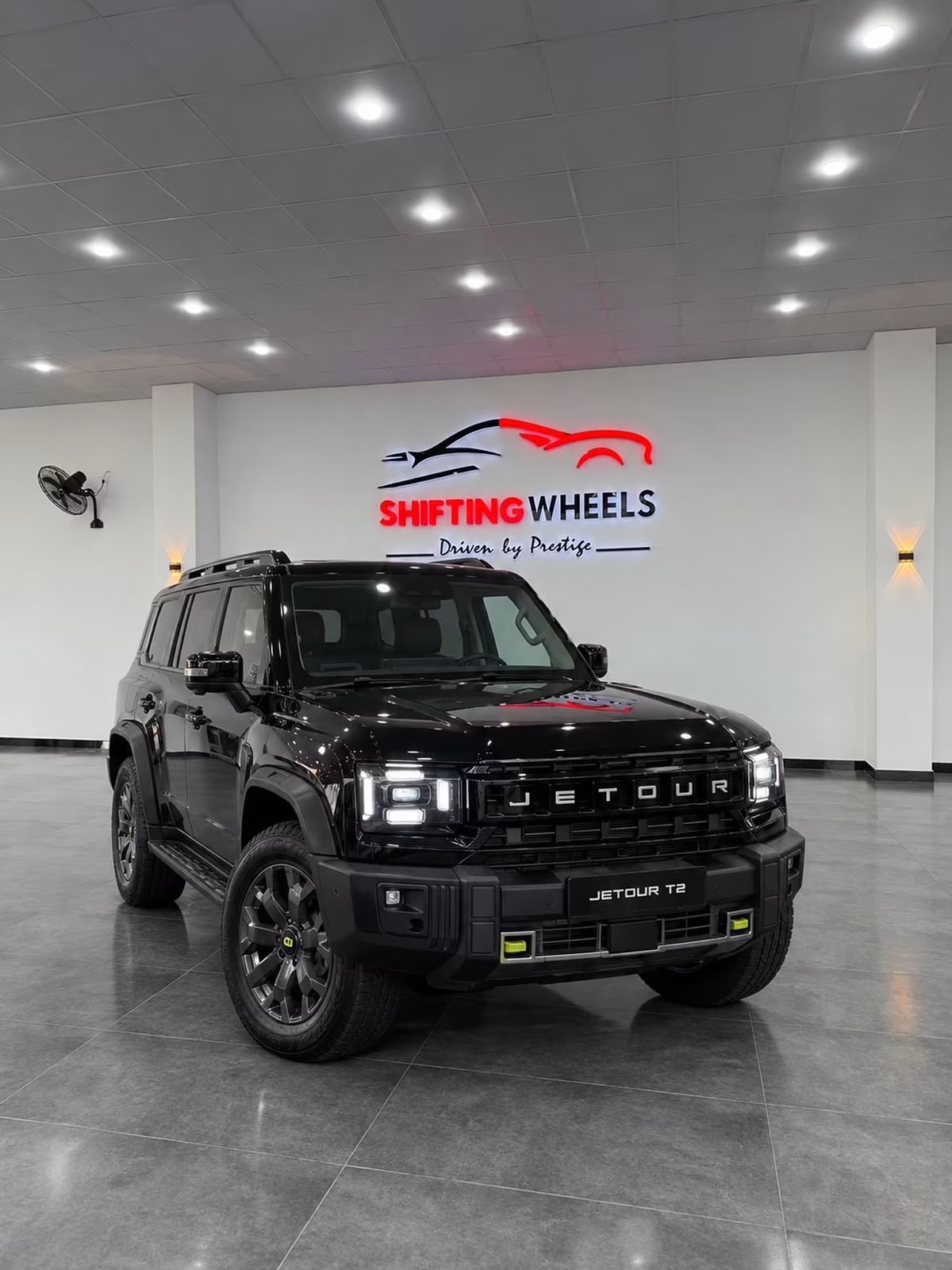 A black SUV on the showroom floor in front of the illuminated Shifting Wheels sign